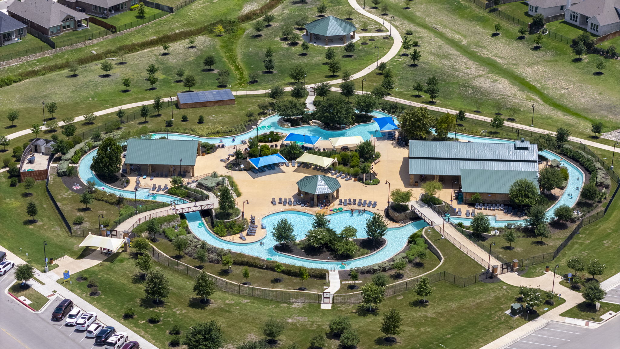 373 Rough Bark Street Buda, TX 78610 - Photo 31 of 39 An aerial view captures a sprawling community pool with a lazy river and adjacent buildings.