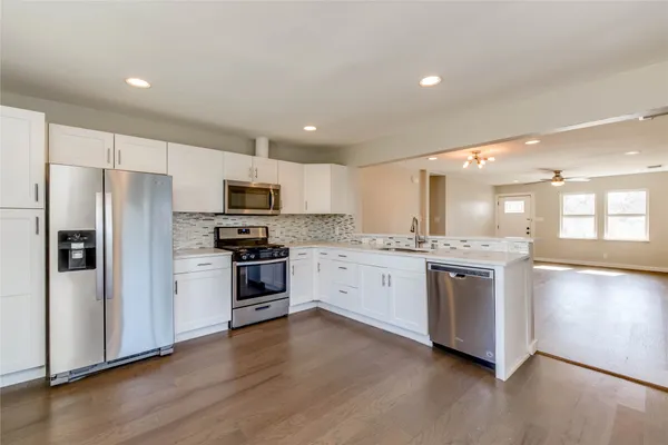 a large kitchen with stainless steel appliances granite countertop a stove a sink and a refrigerator