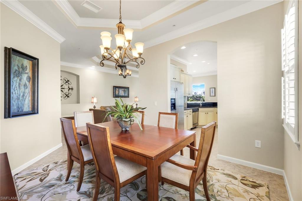 9513 Ironstone Terrace, Unit 202 Naples, FL 34120 - Photo 11 of 47 a dining room with furniture a chandelier and wooden floor