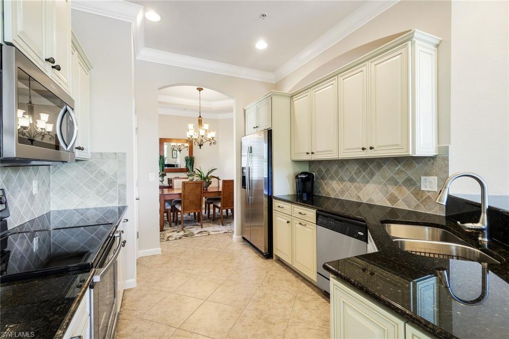 9513 Ironstone Terrace, Unit 202 Naples, FL 34120 - Photo 12 of 47 a kitchen with granite countertop a stove a sink and a microwave