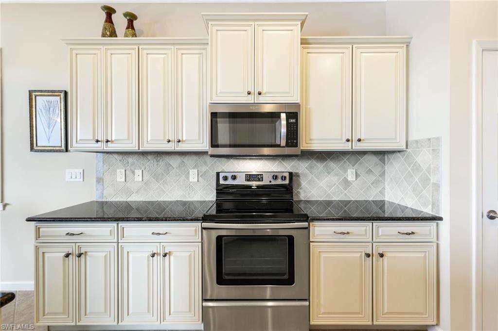 9513 Ironstone Terrace, Unit 202 Naples, FL 34120 - Photo 13 of 47 a kitchen with granite countertop white cabinets and stainless steel appliances