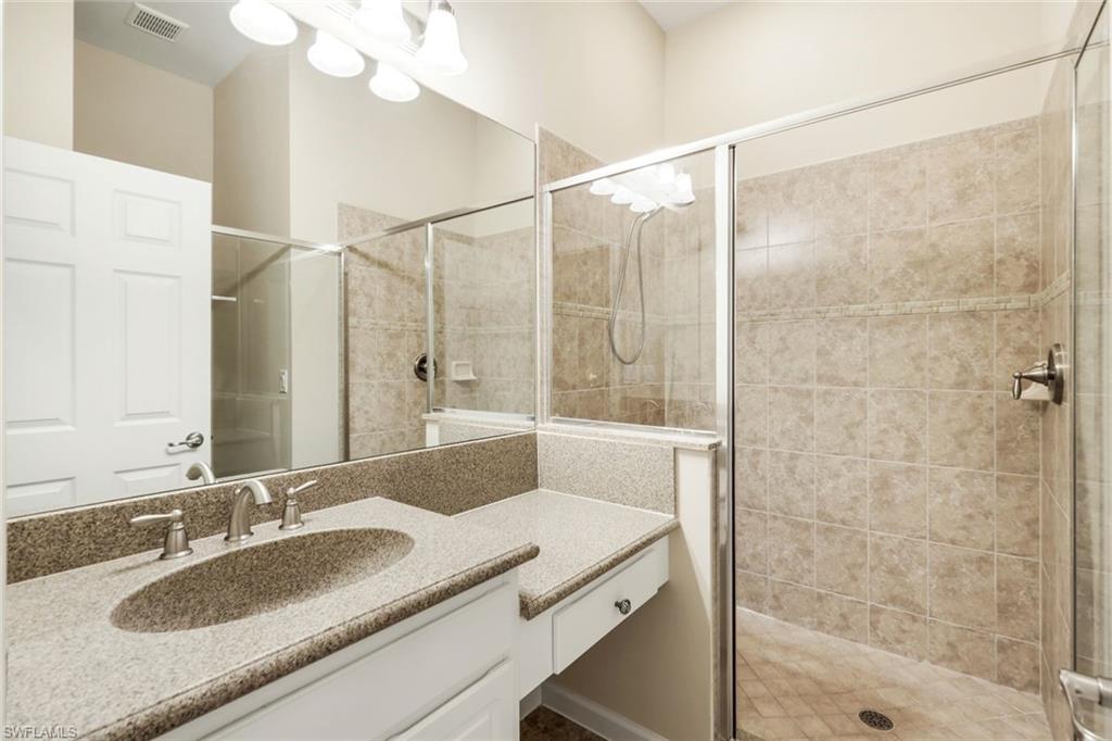 9513 Ironstone Terrace, Unit 202 Naples, FL 34120 - Photo 23 of 47 a bathroom with a granite countertop sink a mirror and a shower