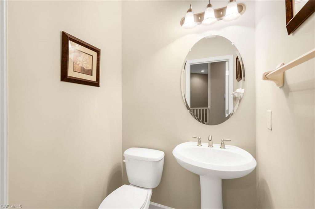 9513 Ironstone Terrace, Unit 202 Naples, FL 34120 - Photo 25 of 47 a bathroom with a toilet sink and mirror
