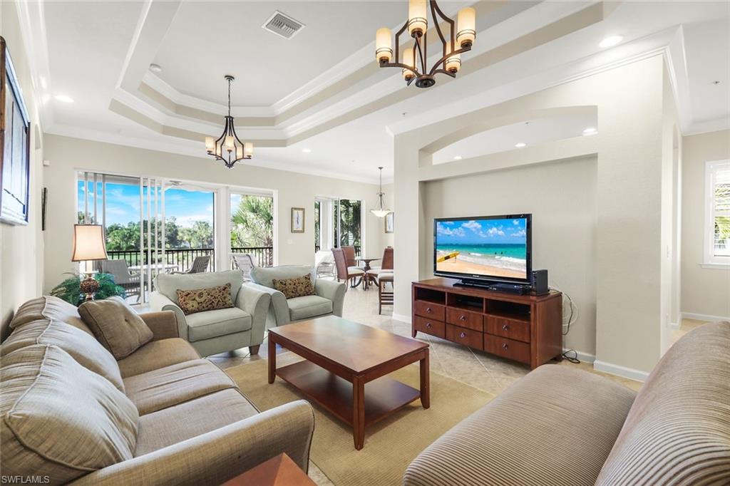 9513 Ironstone Terrace, Unit 202 Naples, FL 34120 - Photo 7 of 47 a living room with furniture a chandelier and a flat screen tv