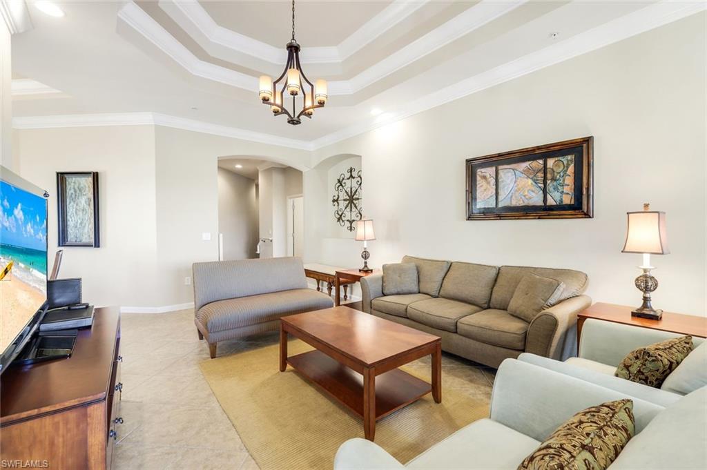 9513 Ironstone Terrace, Unit 202 Naples, FL 34120 - Photo 9 of 47 a living room with furniture a chandelier and a window