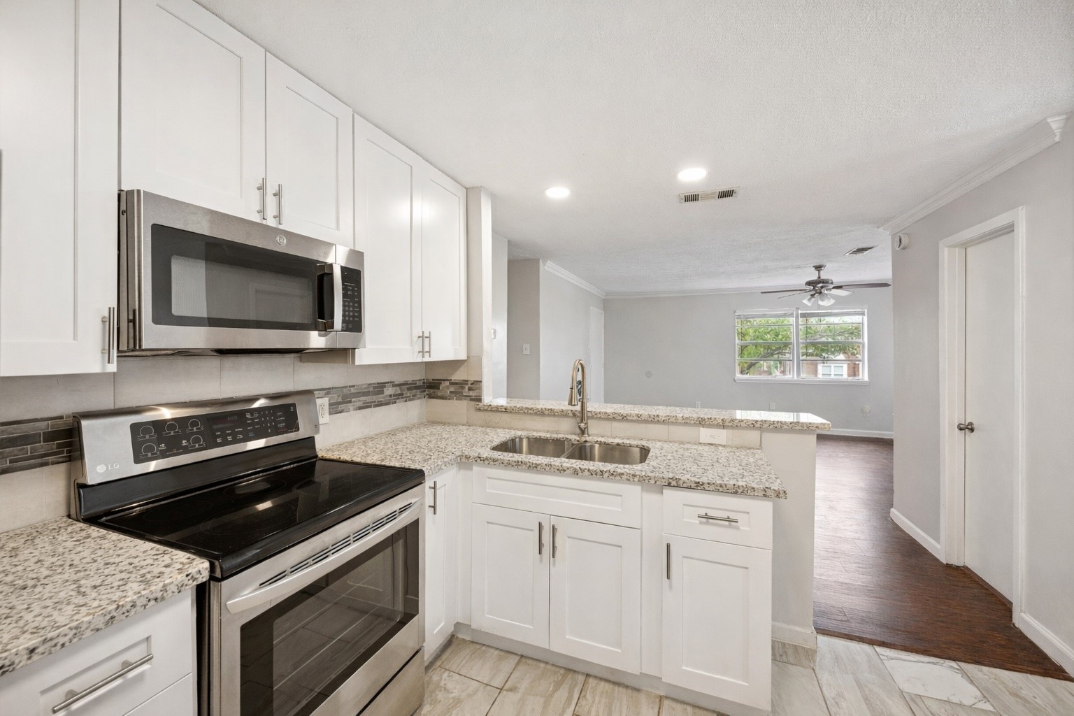 2614 Cleburne Street Houston, TX 77004 - Photo 9 of 22 A chef’s workspace engineered for conversation. Striking granite countertops and updated cabinetry pair beautifully with durable tile flooring, anchored by a breakfast bar that overlooks the living area.