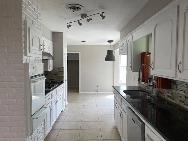 a kitchen with granite countertop a sink stove and cabinets