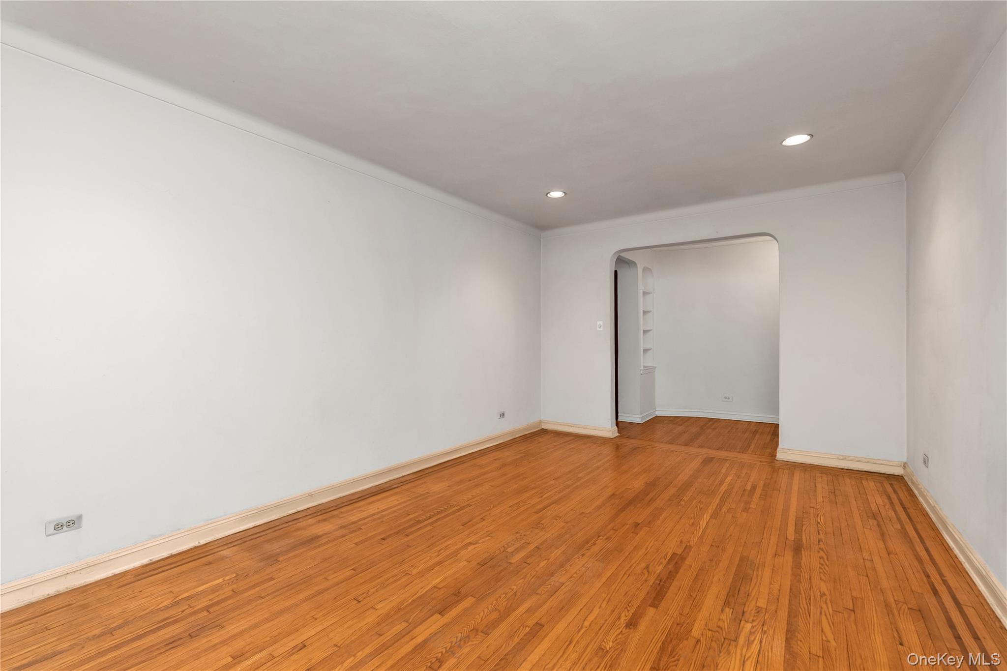 76-12 35th Avenue, Unit 1B Queens, NY 11372 - Photo 11 of 22 Spare room featuring arched walkways, recessed lighting, and light wood finished floors