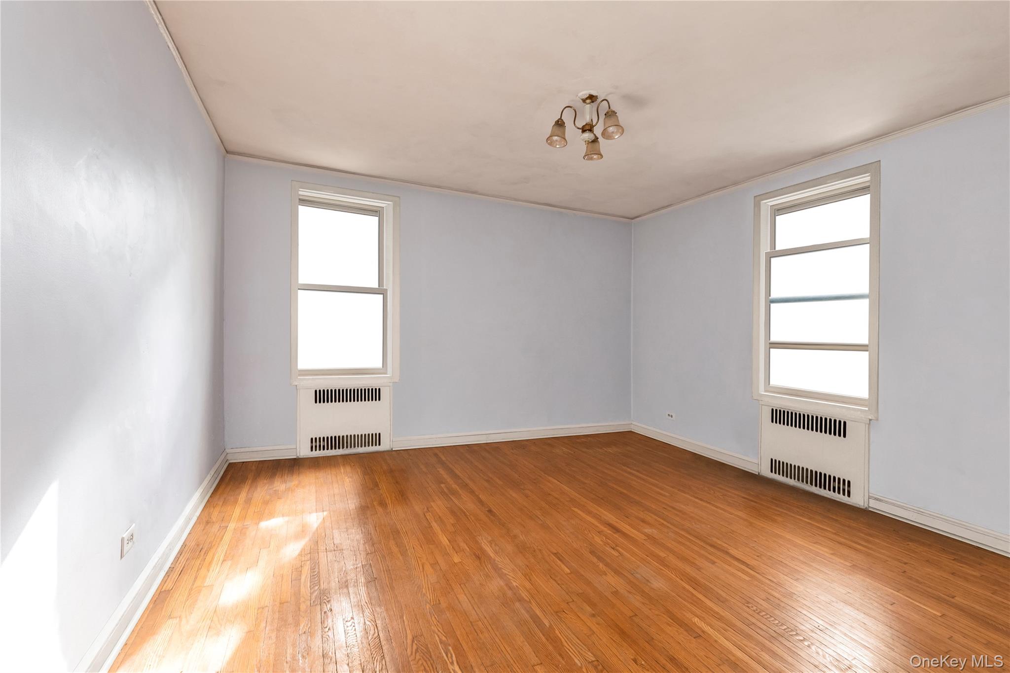 76-12 35th Avenue, Unit 1B Queens, NY 11372 - Photo 20 of 22 Unfurnished room featuring light wood finished floors and radiator
