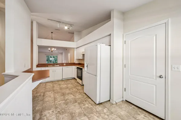 a kitchen with a refrigerator and white cabinets