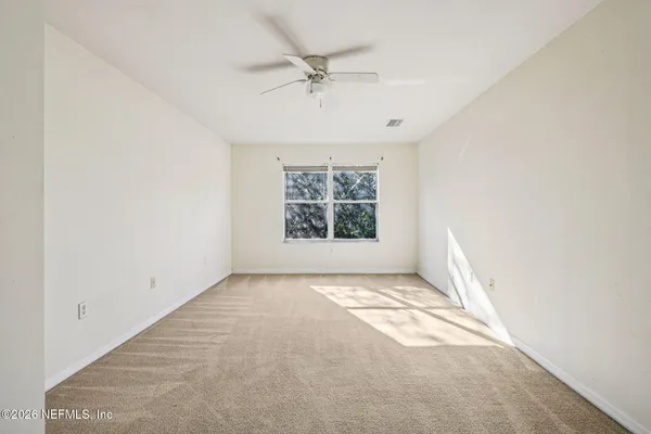 an empty room with a window and a ceiling fan