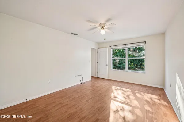 an empty room with a window and ceiling fan