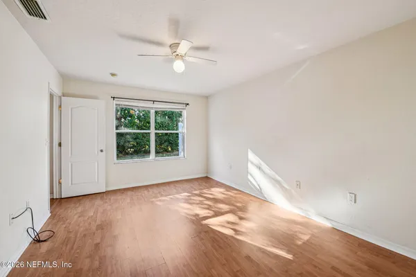 a view of empty room with wooden floor and fan