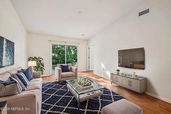 a living room with furniture a flat screen tv and a window