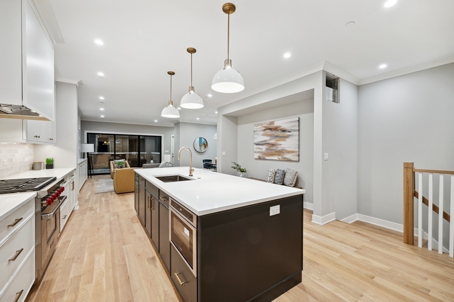 2004 West Addison Street, Unit 1E Chicago, IL 60618 - Photo 10 of 27 a large kitchen with stainless steel appliances a stove a sink dishwasher and a dining table with wooden floor