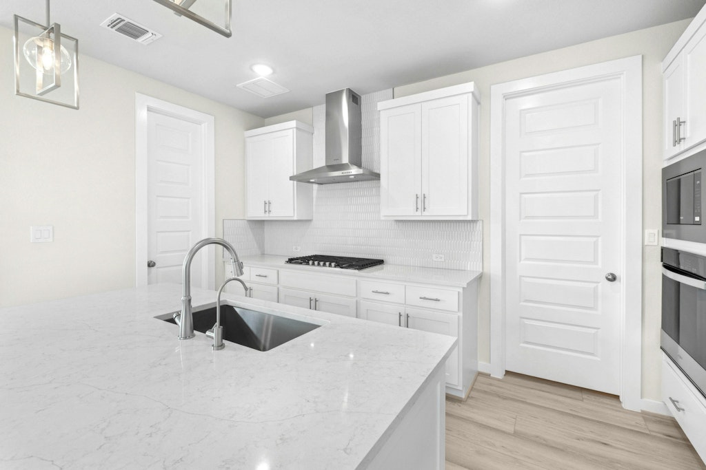 4733 Pleasant Place Round Rock, TX 78665 - Photo 8 of 33 a kitchen with stainless steel appliances a sink dishwasher a stove and white cabinets with wooden floor