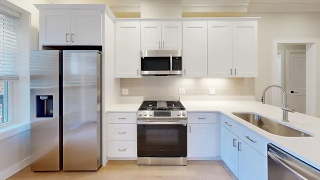 a kitchen with white cabinets and stainless steel appliances