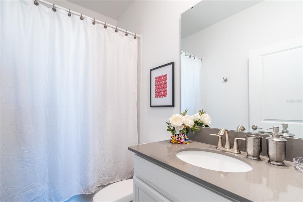 3032 Protagonist Street Kissimmee, FL 34746 - Photo 18 of 34 a bathroom with a granite countertop sink and a mirror with toilet