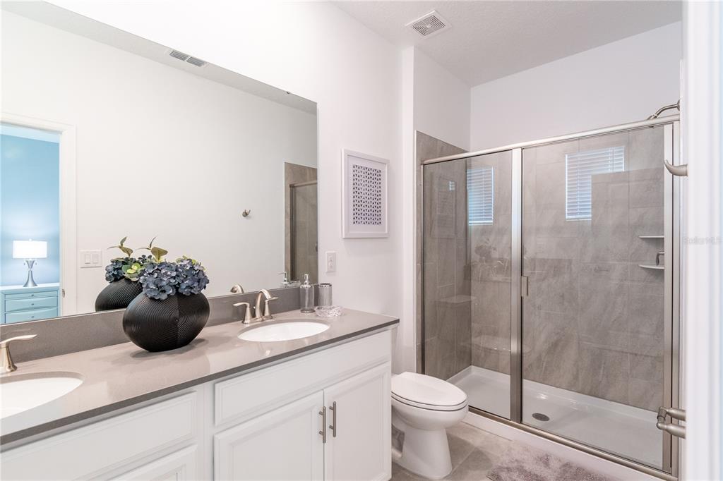 3032 Protagonist Street Kissimmee, FL 34746 - Photo 21 of 34 a bathroom with a granite countertop sink a toilet and shower