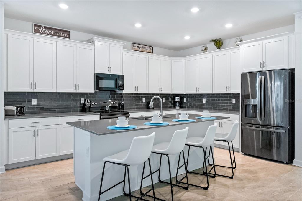 3032 Protagonist Street Kissimmee, FL 34746 - Photo 9 of 34 a kitchen with stainless steel appliances granite countertop a stove a sink a microwave a refrigerator and white cabinets