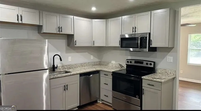 a kitchen with stainless steel appliances granite countertop white cabinets a stove top oven a sink and dishwasher