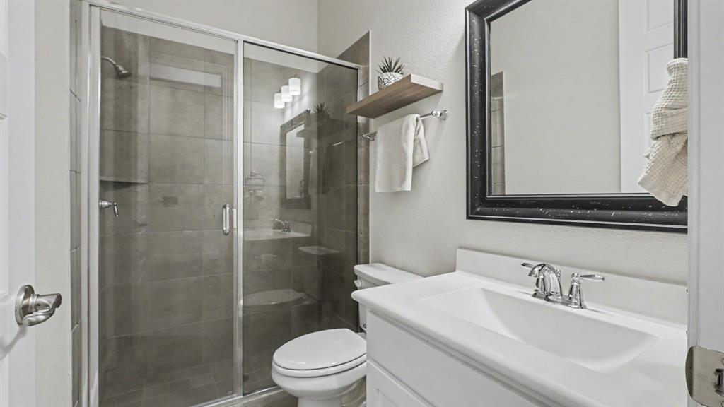 5213 Ravine Ridge Court Flower Mound, TX 76262 - Photo 13 of 40 Bathroom featuring a glass-enclosed walk-in shower with large tile, a single vanity with an integrated sink, chrome fixtures, and a framed mirror.