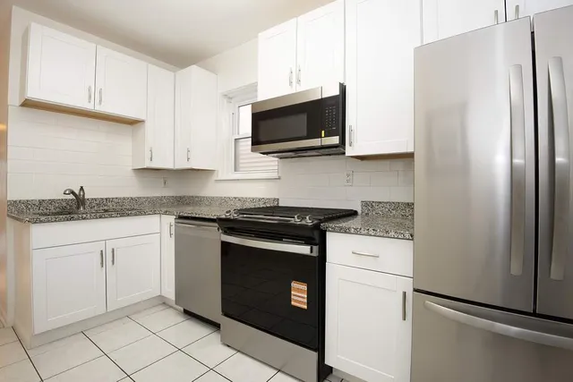 a kitchen with granite countertop white cabinets stainless steel appliances and a sink