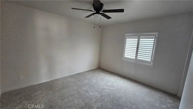 an empty room with a window and a ceiling fan