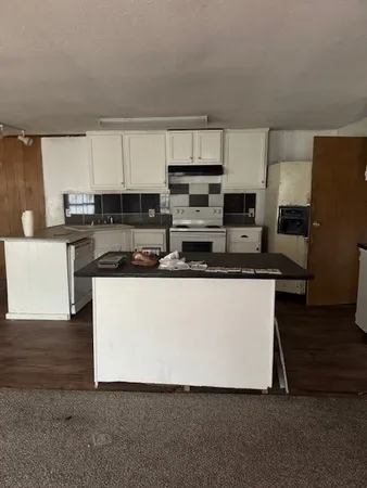 a white kitchen with stainless steel appliances a sink a stove a microwave a refrigerator a sink and cabinets