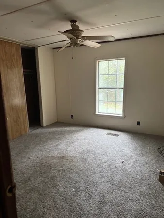 an empty room with windows and fan