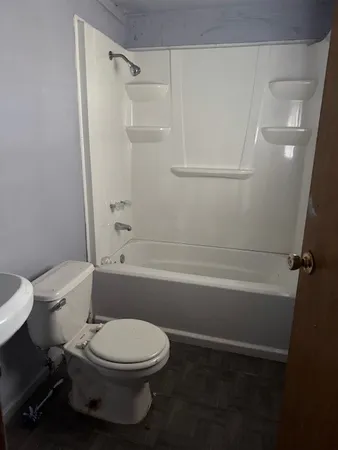 a white toilet and tub next to a bathroom sink