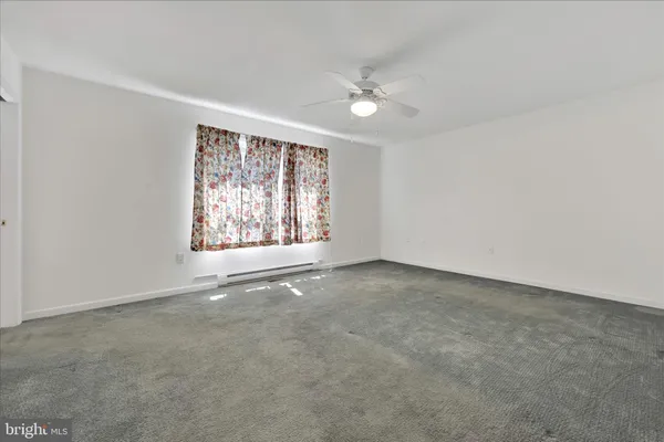 an empty room with windows and chandelier fan