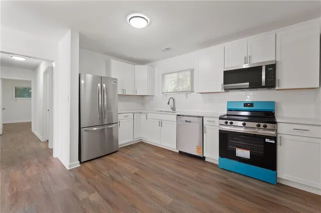 a kitchen with stainless steel appliances a refrigerator stove and white cabinets
