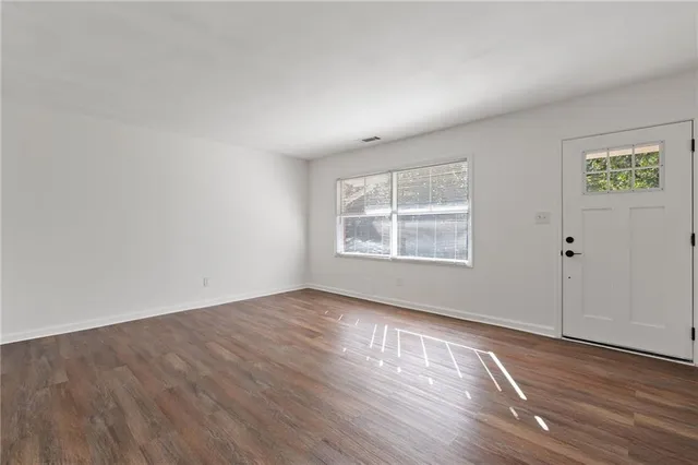 an empty room with wooden floor and windows