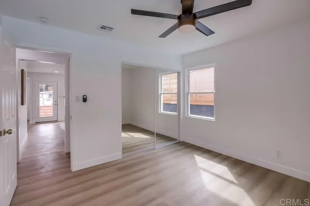 an empty room with wooden floor and ceiling fan