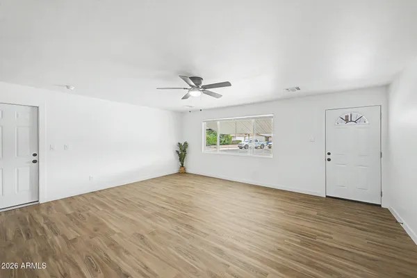an empty room with wooden floor and ceiling fan