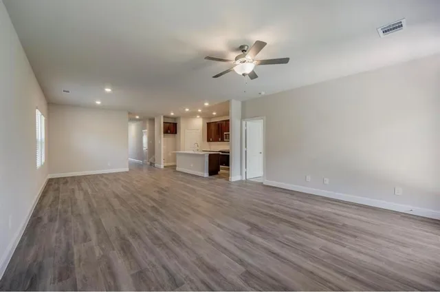 a view of empty room with wooden floor and ceiling fan