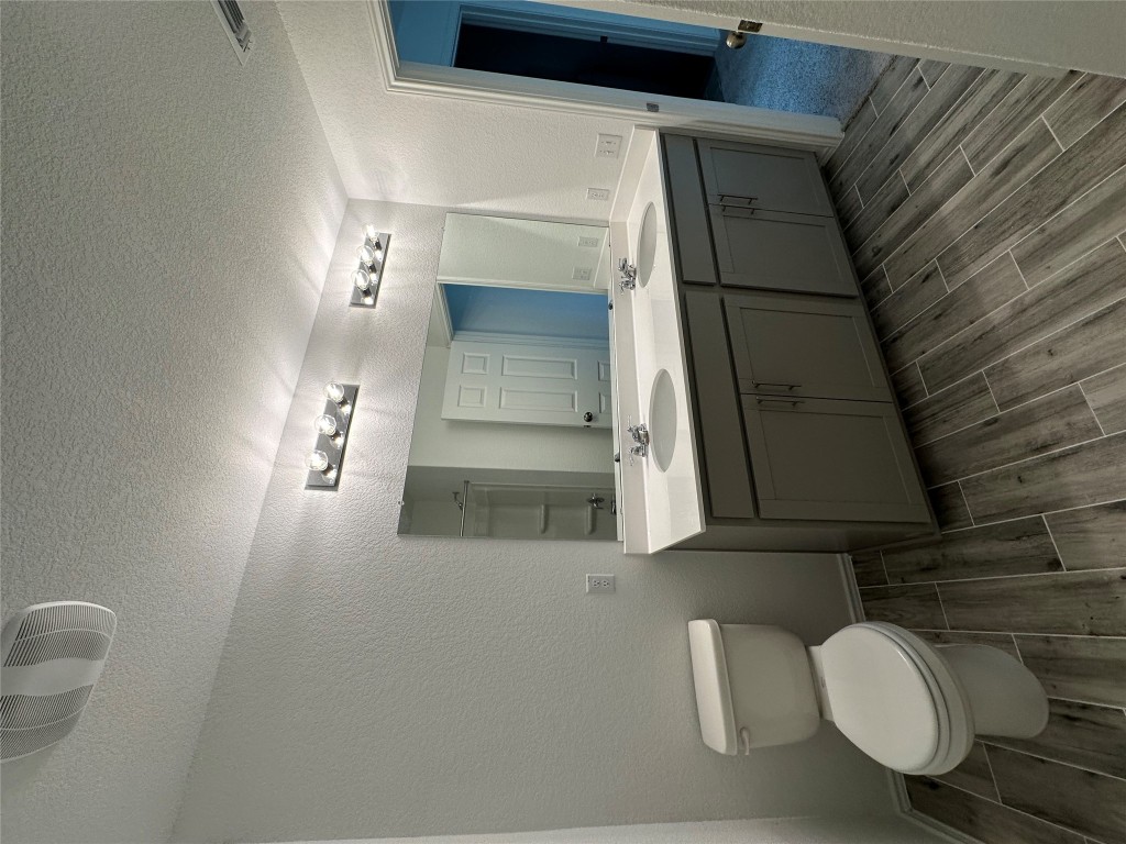 253 Redonda Drive Liberty Hill, TX 78642 - Photo 11 of 18 a bathroom with a granite countertop toilet a sink and a mirror