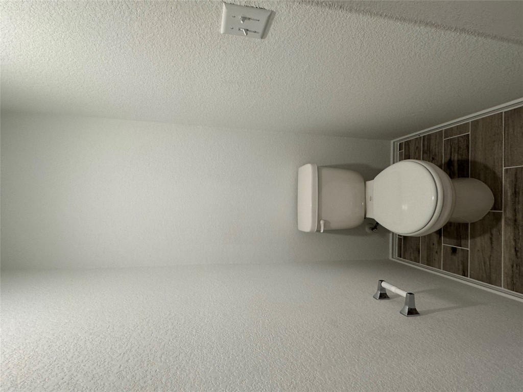 253 Redonda Drive Liberty Hill, TX 78642 - Photo 8 of 18 a white toilet sitting in a bathroom next to a wooden wall