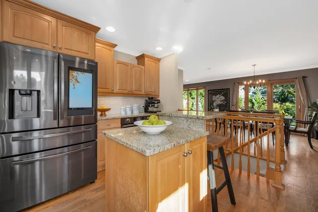 a kitchen with stainless steel appliances granite countertop a stove a sink dishwasher and a refrigerator with wooden floor