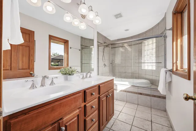 a bathroom with a double vanity sink a toilet a mirror and shower