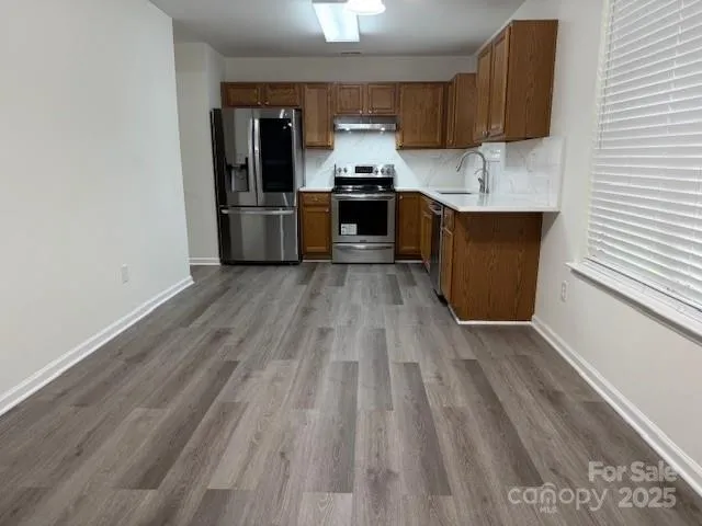 a kitchen with stainless steel appliances granite countertop a refrigerator and a stove top oven
