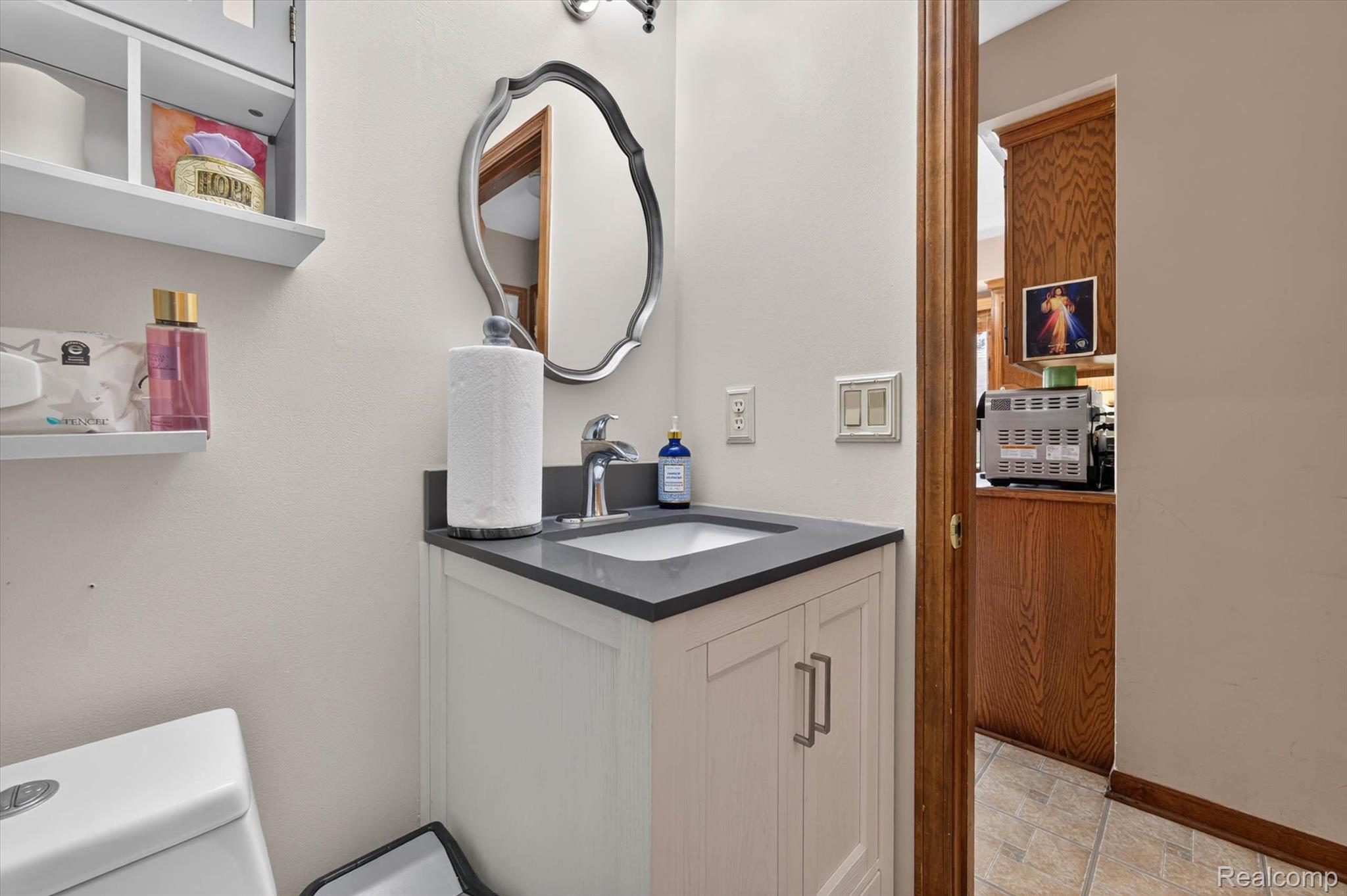 46362 Springhill Drive Utica, MI 48317 - Photo 29 of 59 Bathroom featuring a white vanity with panel-front cabinetry and silver hardware, a dark countertop, and an undermount sink with a chrome faucet