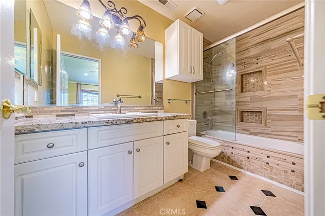 a bathroom with a granite countertop toilet sink and mirror