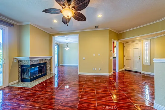 a view of a livingroom with a fireplace a ceiling fan and front door