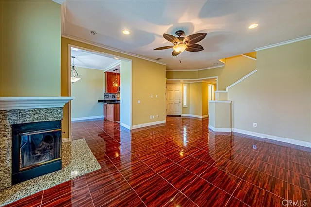 a view of a livingroom with wooden floor a ceiling fan and a fireplace