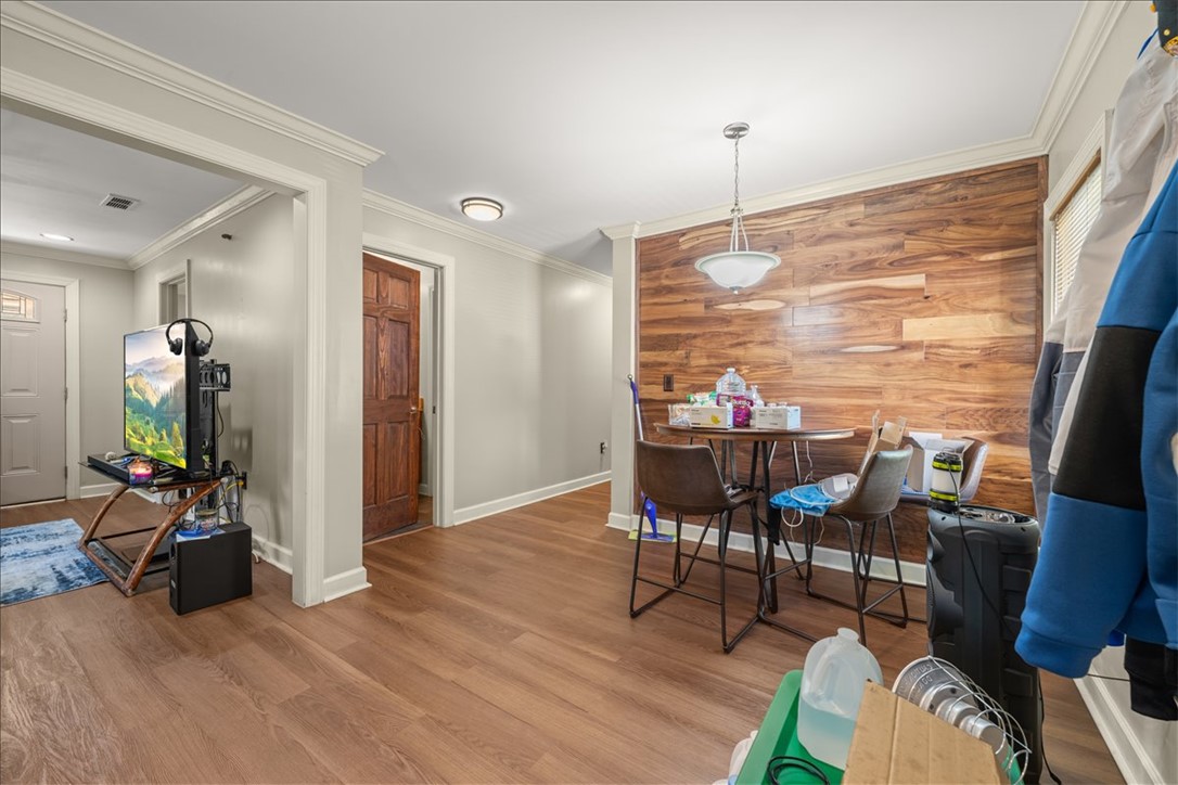 412 Sanders Street Anderson, SC 29624 - Photo 14 of 30 Rich hardwood-look flooring complements an accent wall, creating a defined eating area with overhead pendant lighting.