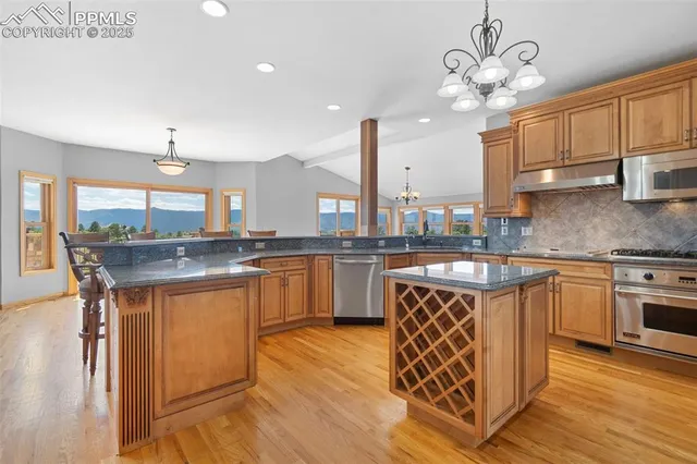 a kitchen with stainless steel appliances granite countertop a sink a stove and a wooden floors