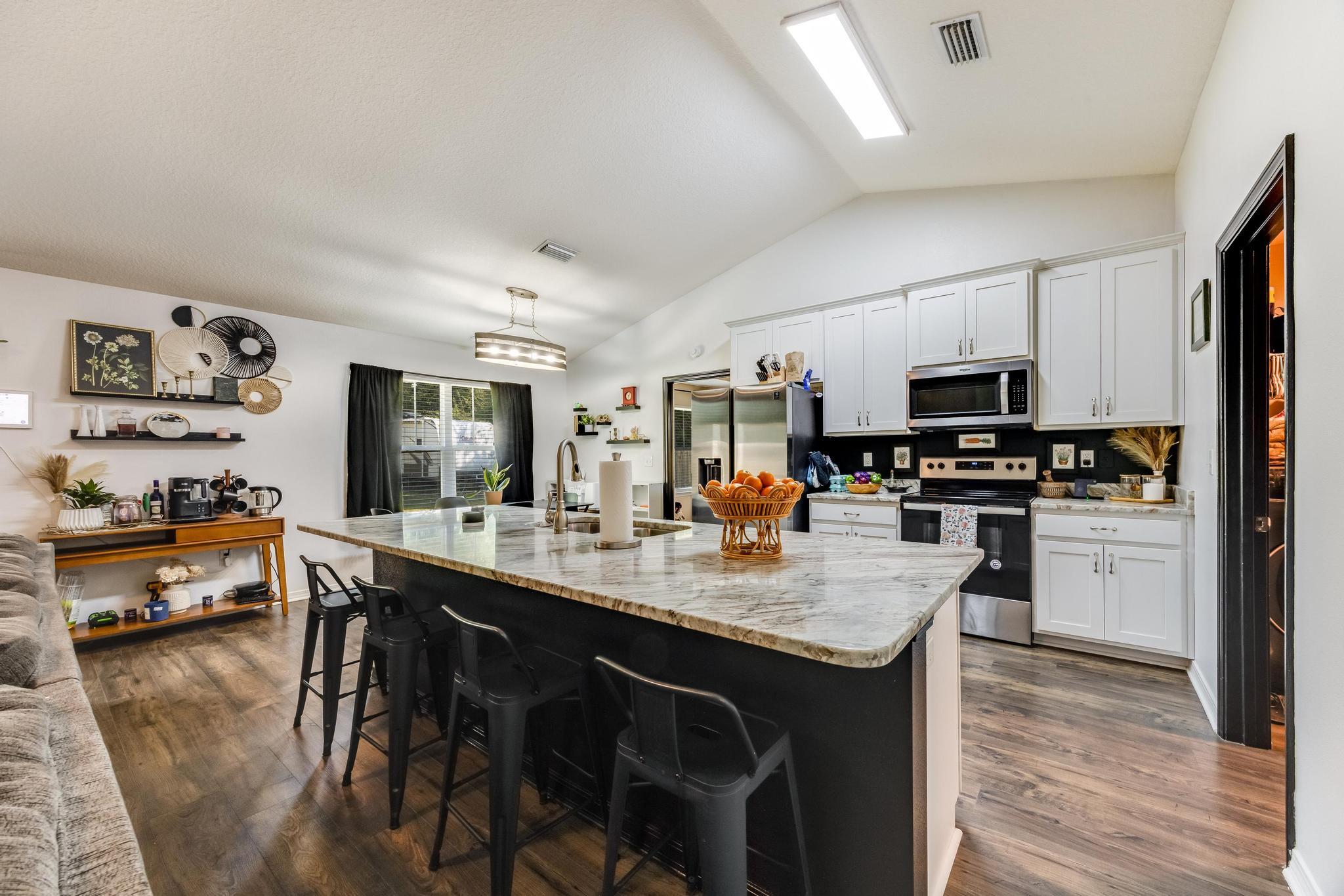 3381 Auburn Road Crestview, FL 32539 - Photo 8 of 46 a kitchen with stainless steel appliances granite countertop a stove a refrigerator a sink a dining table and chairs with wooden floor