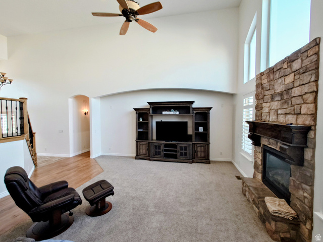 552 Sunset Crest Way Draper, UT 84020 - Photo 13 of 68 Living area with a towering ceiling, a fireplace, arched walkways, ceiling fan, and light carpet